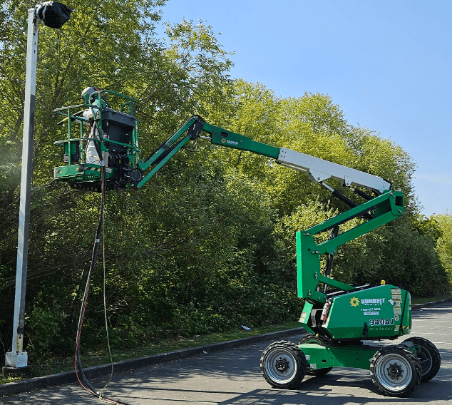 sandblasting removing rust and corrosion from a light post in a parking lot
